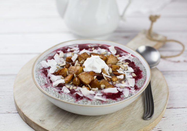 Chia seed porridge with yoghurt on top, on brown board with teapot behind.