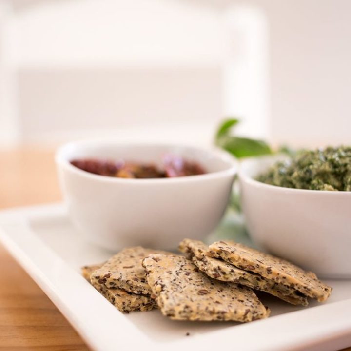 Gluten-Free Crackers on white platter on table with a chair in the background.