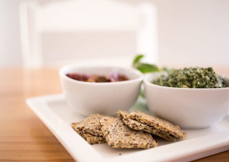 Gluten-Free Crackers on white platter on table with a chair in the background.