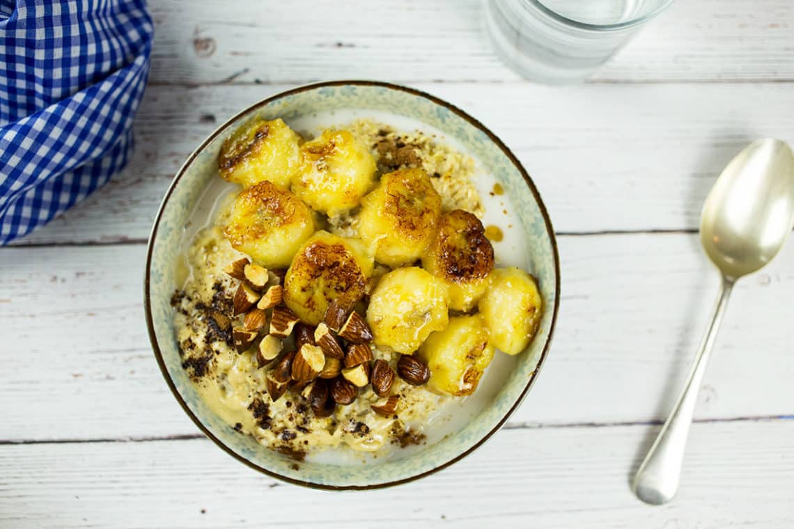 Tahini Oatmeal in bowl on white wooden background with blue and white cloth behind.