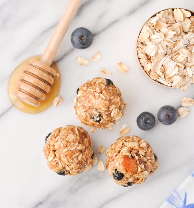 No-Bake Almond Blueberry Snacks on marble background with honey, oats and blueberries in background.