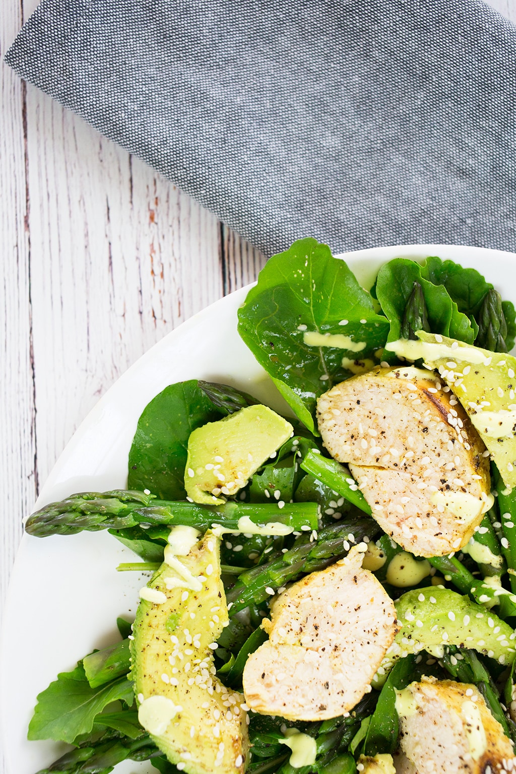 Close up of chicken, avocado and asparagus salad on grey napkin with lemon cashew dressing.