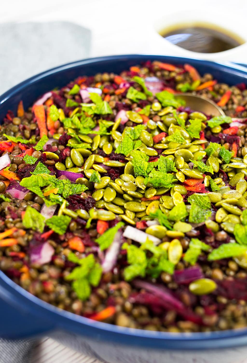 Close up of lentil salad wirh spoon in the lentils in a blue bowl.