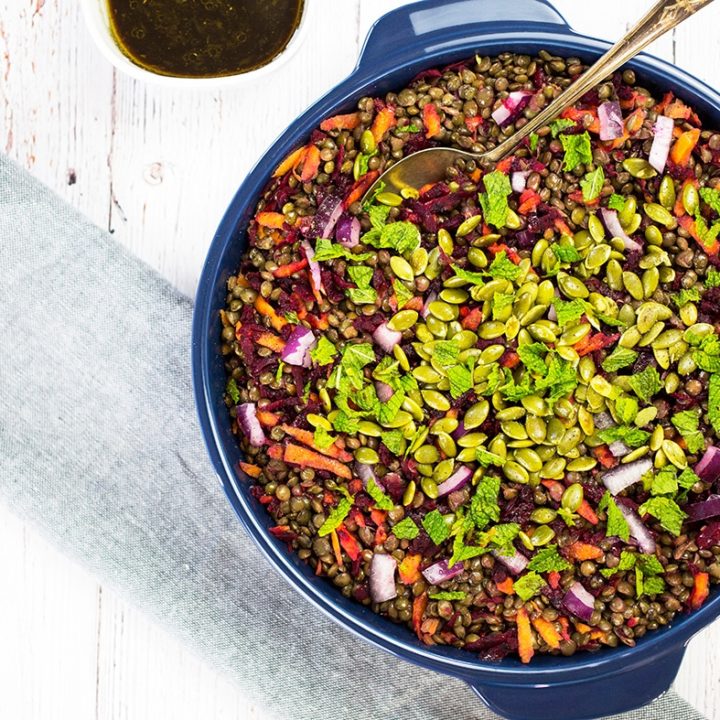 Loaded Lentil Salad with spoon and dressing on side