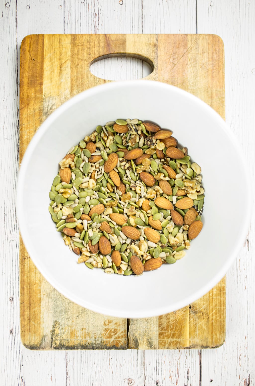 Nuts and seeds in white bowl for making the bread. Bowl is on chopping board.