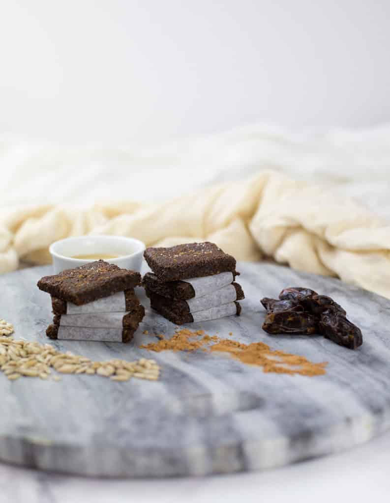 Carob and Tahini Seed Bars on grey marble chopping board with white cloth in the background