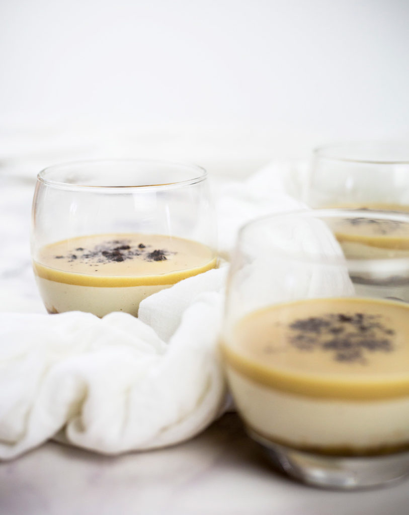 Vertical photo of three salted caramel dessert pots with a white cloth drapped around them.