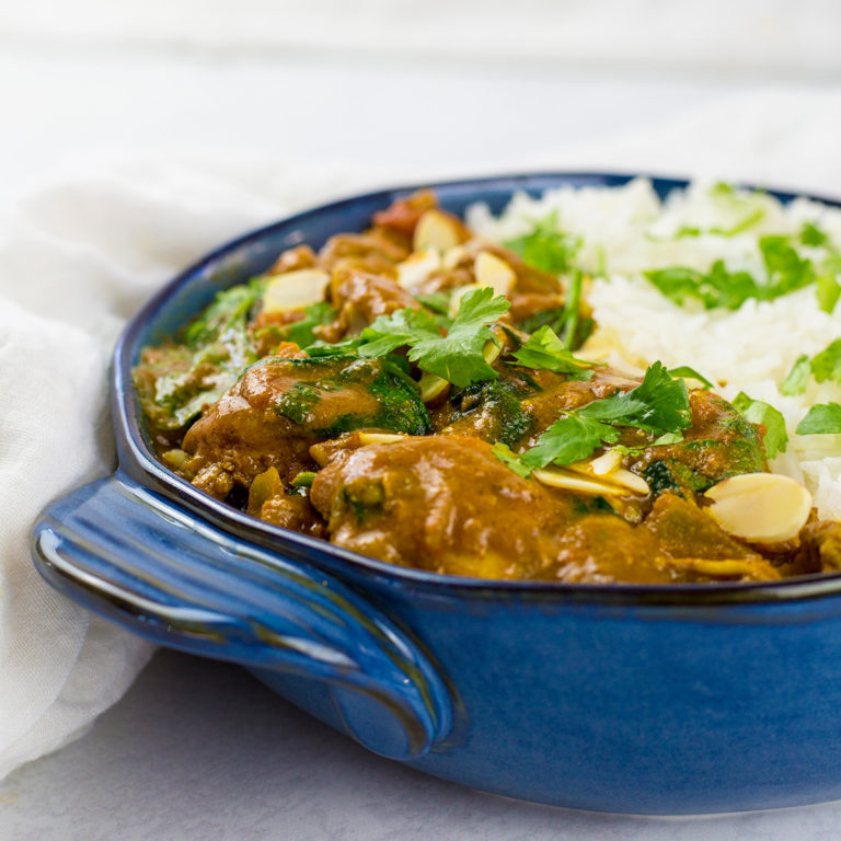Close up of coconut chicken curry in blue bowl.