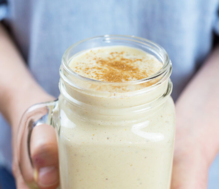 Hands showing salted caramel smoothie in glass mug.