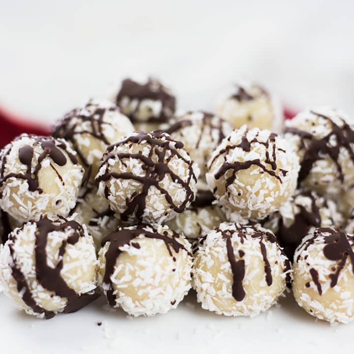Coconut almond snowballs on white background with red cloth behind.