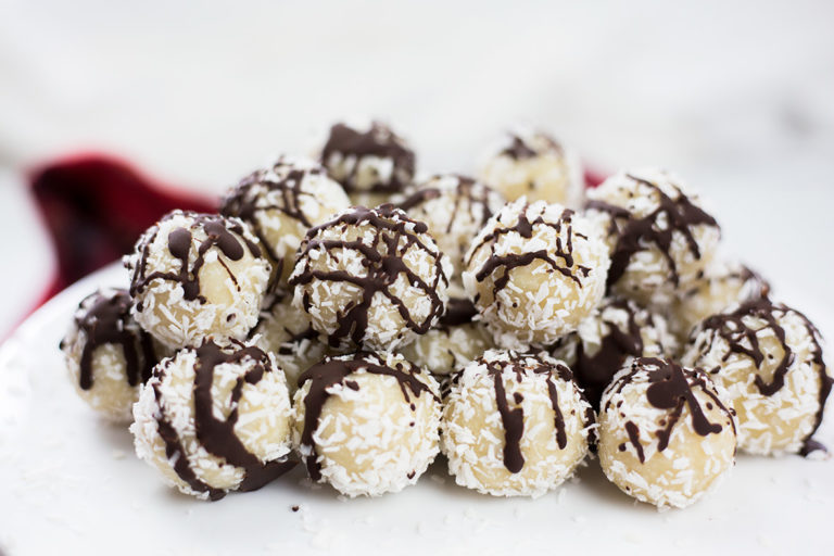 Coconut almond snowballs on white background with red cloth behind.