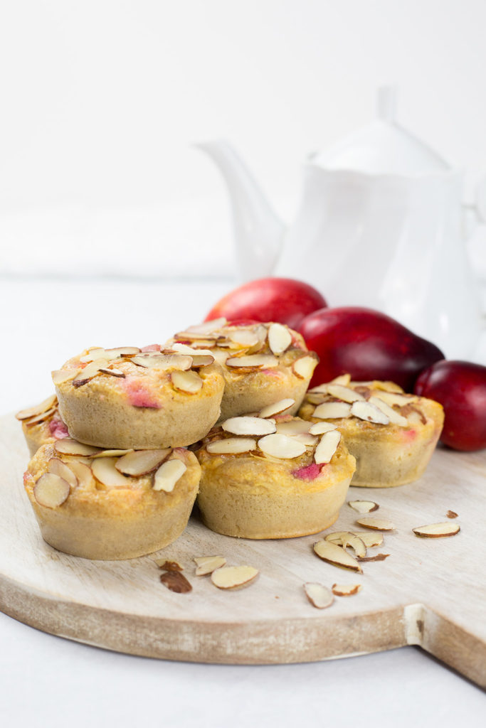 Vertical image of buckwheat plum muffins with teapot in background