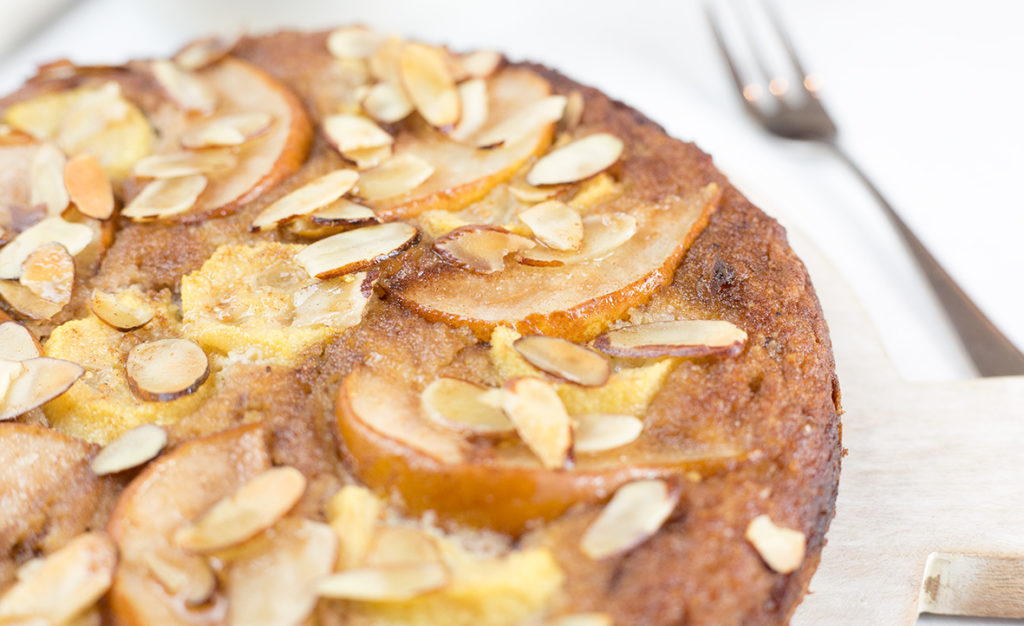 Close up of feijoa and pear cake on white background with fork to the right