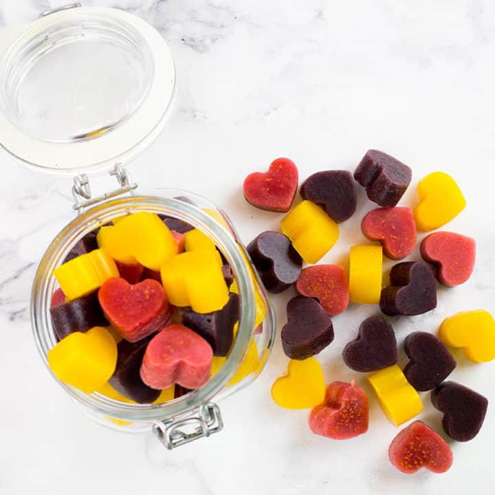 Birdseye view of gummies in jar with some outside of the jar on a marble background.