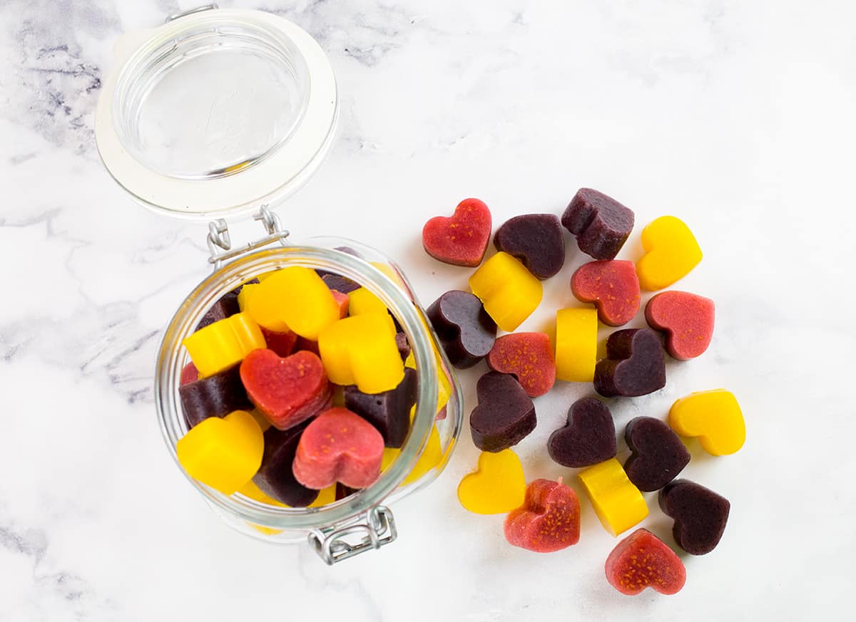 Birdseye view of gummies in jar with some outside of the jar on a marble background.