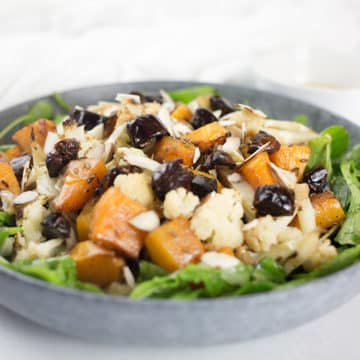 Close up of pumpkin and cauliflower salad in blue bowl with white background.