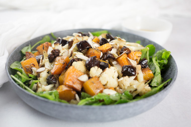 Close up of pumpkin and cauliflower salad in blue bowl with white background.