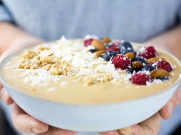 Peach Smoothie Bowl being held by a ladies hands.