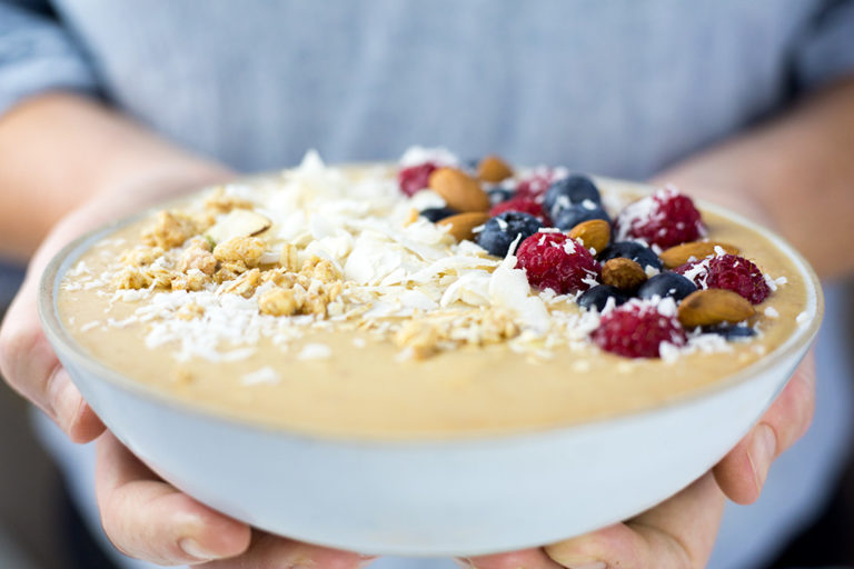 Peach Smoothie Bowl being held by a ladies hands.