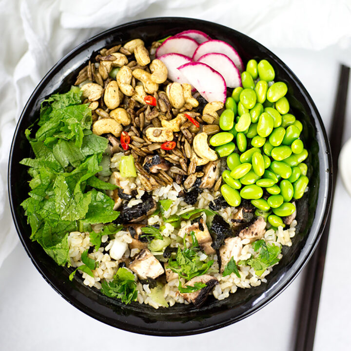 Close up of Asian Rice Bowl in a black bowl with chopsticks to the right on a white background.