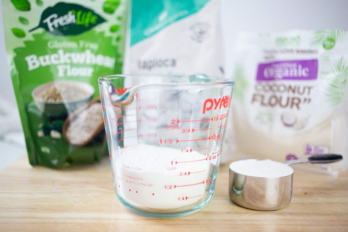 Selection of gluten free flours with flour in a jug and some in a measuring cup.