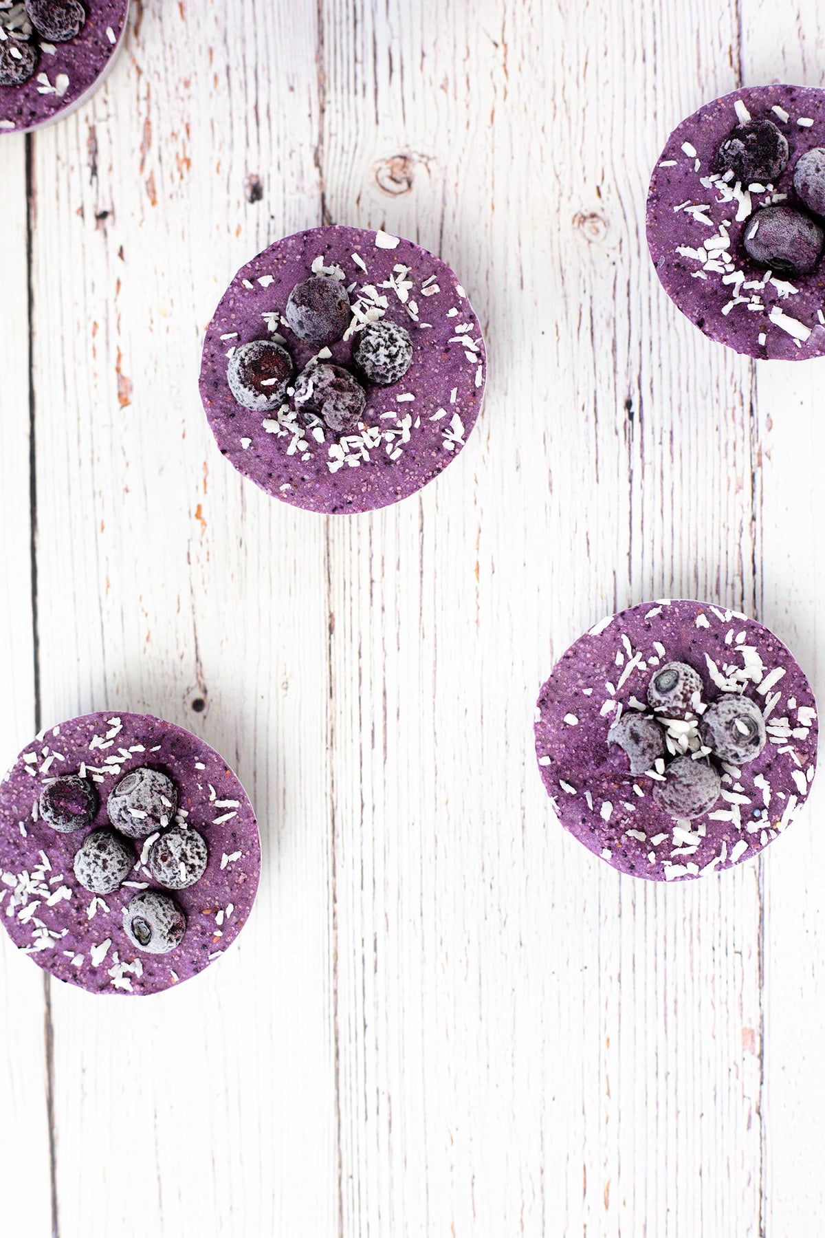 Birdseye view of blueberry Vegan cheesecakes on wooden white background.