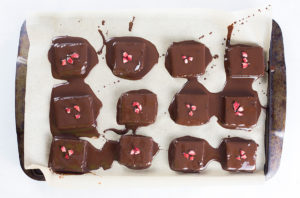 Brownies dipped in chocolate on tray.