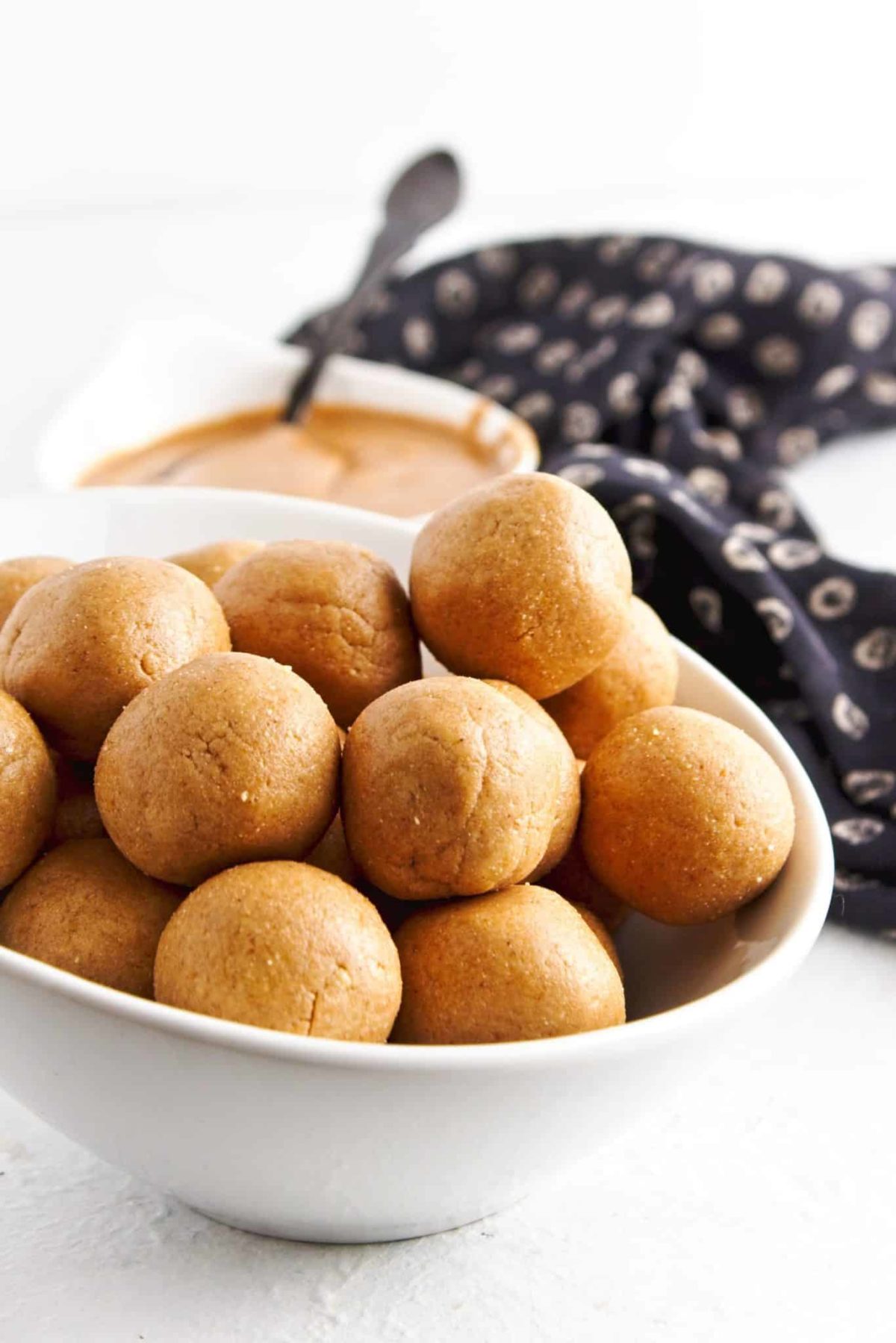 Close up of peanut butter protein balls with bowl of peanut butter behind.