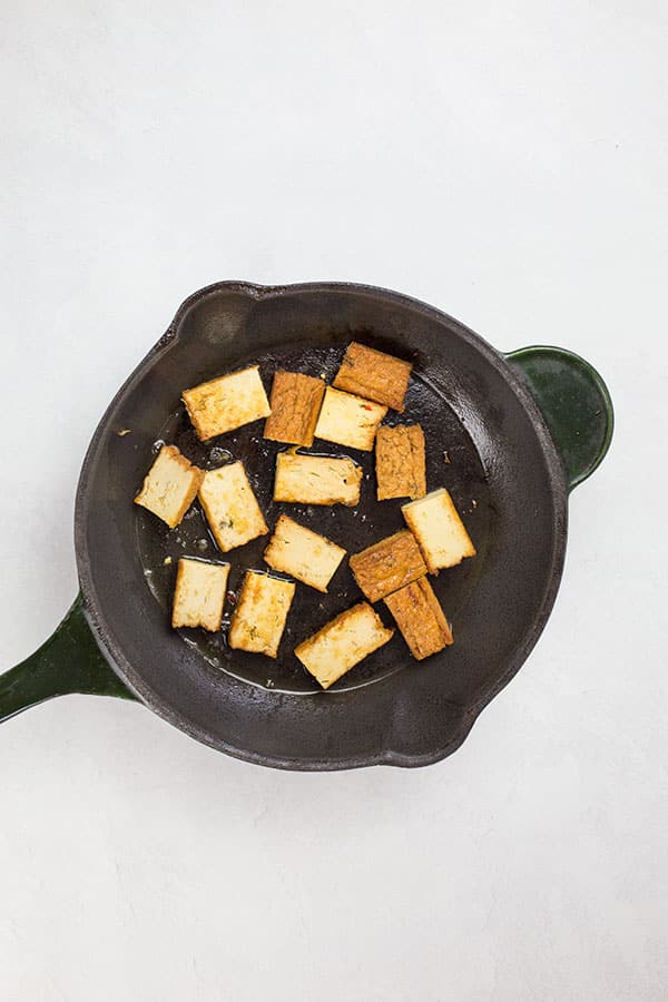 Tofu cooking in pan.