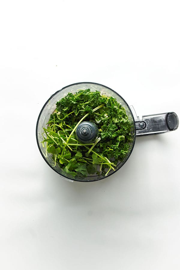 Fresh herbs added into food processor for chimichurri.