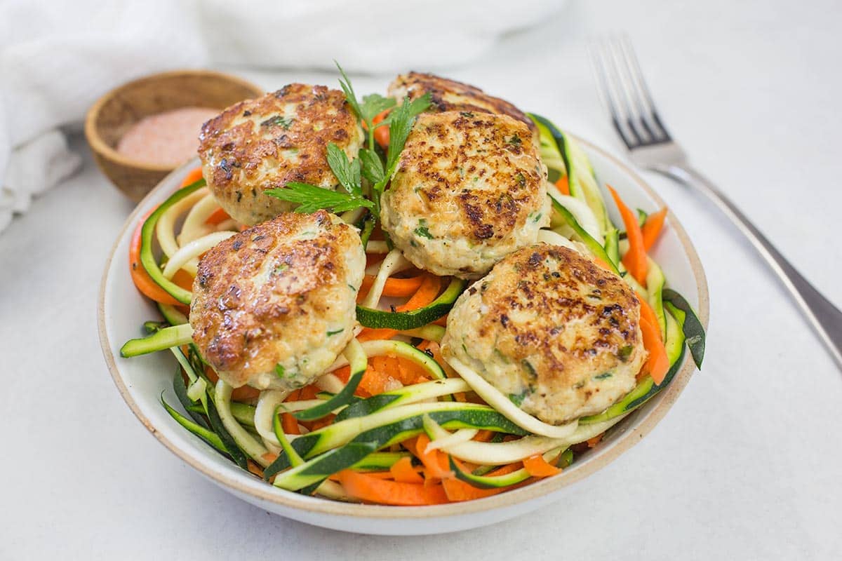 Gluten-free chicken meatballs on bowl of zoodles.