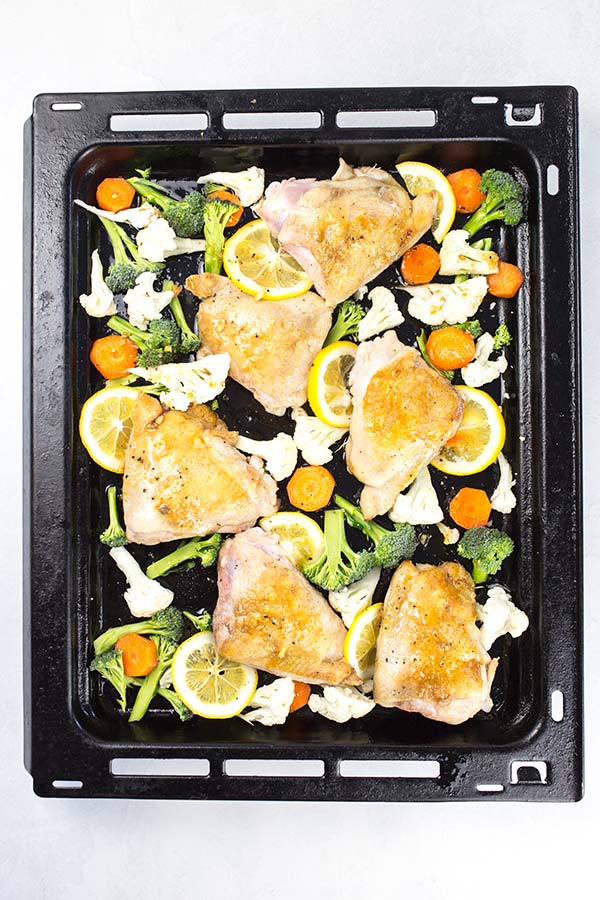 Lemon pepper chicken thighs and veggies on oven tray to bake.