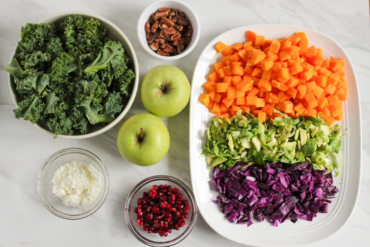 Bowl of kale, apples, slices squash, brussels sprouts, cabbage, pomegranate for salad