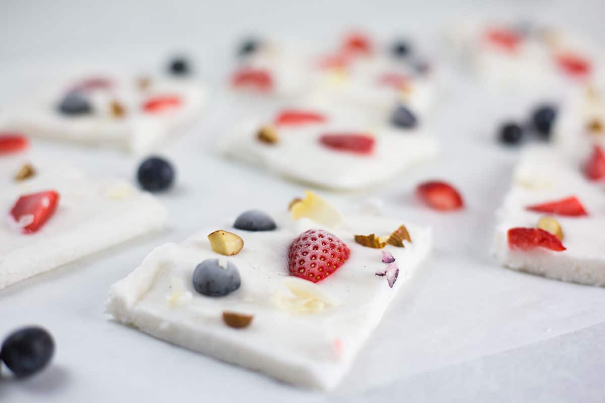 Close up of sliced yoghurt bars with blueberry in front on white background.