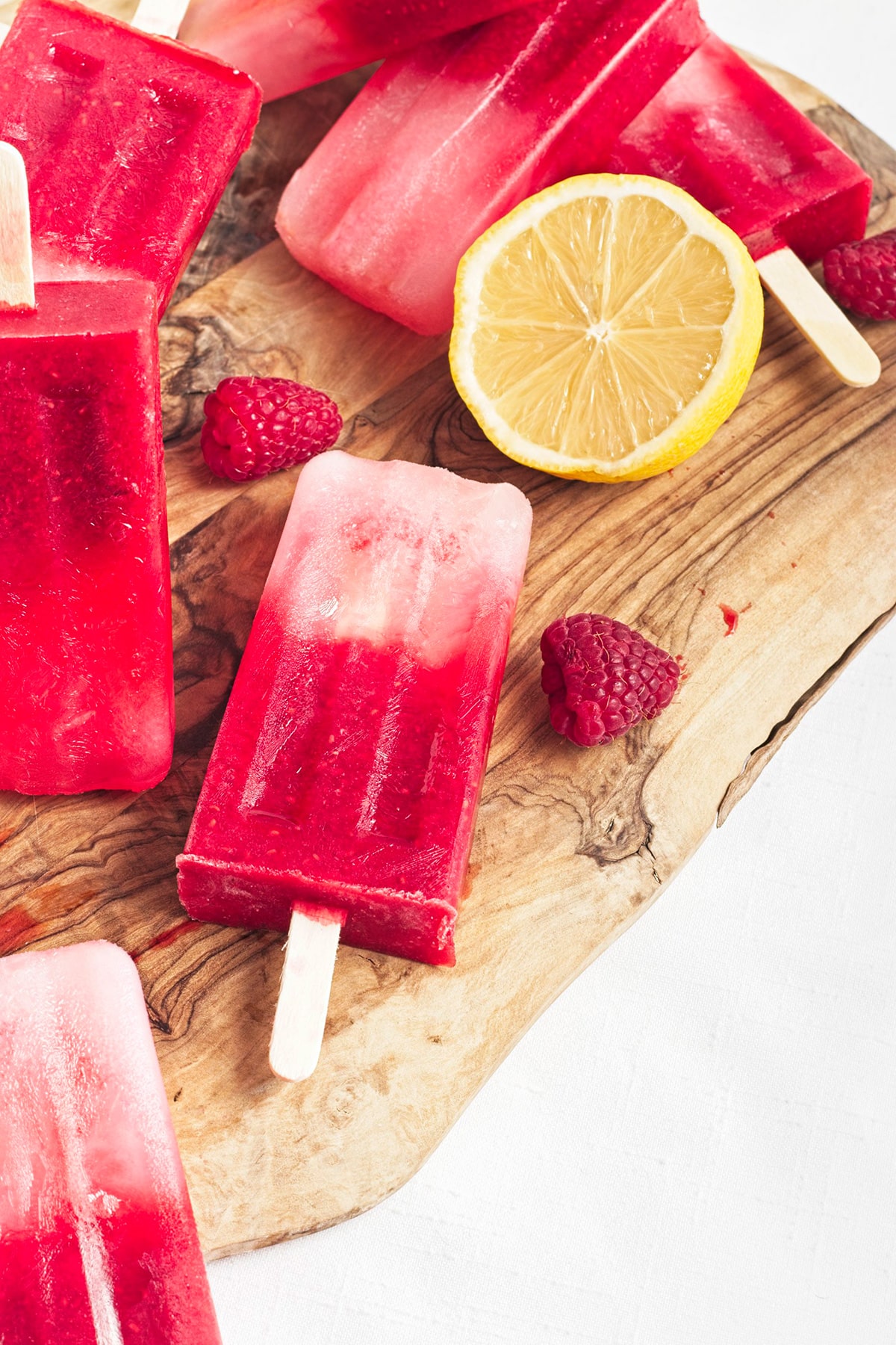Rapsberry lemonade popsicles piled on top of each other on board.